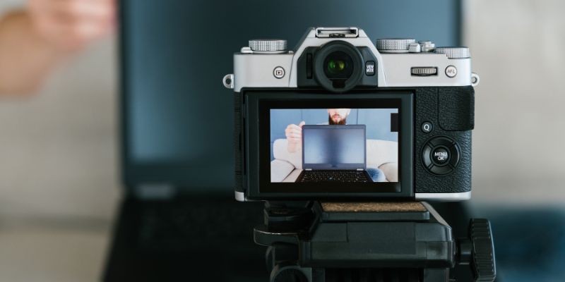 A digital camera records a content creator using a laptop, showcasing the melding of AI and human creativity in content production.